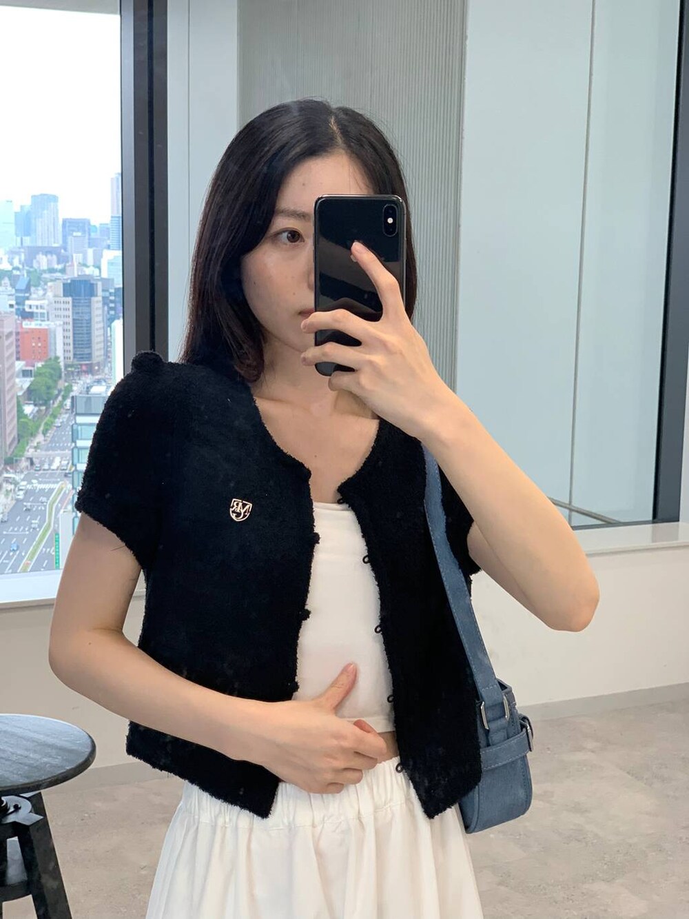 ホワイト系のスカート、ブルー系のトートバッグ、ブラック系のカーディガン/ボレロを着用したレディースの夏コーディネートの3枚目の写真