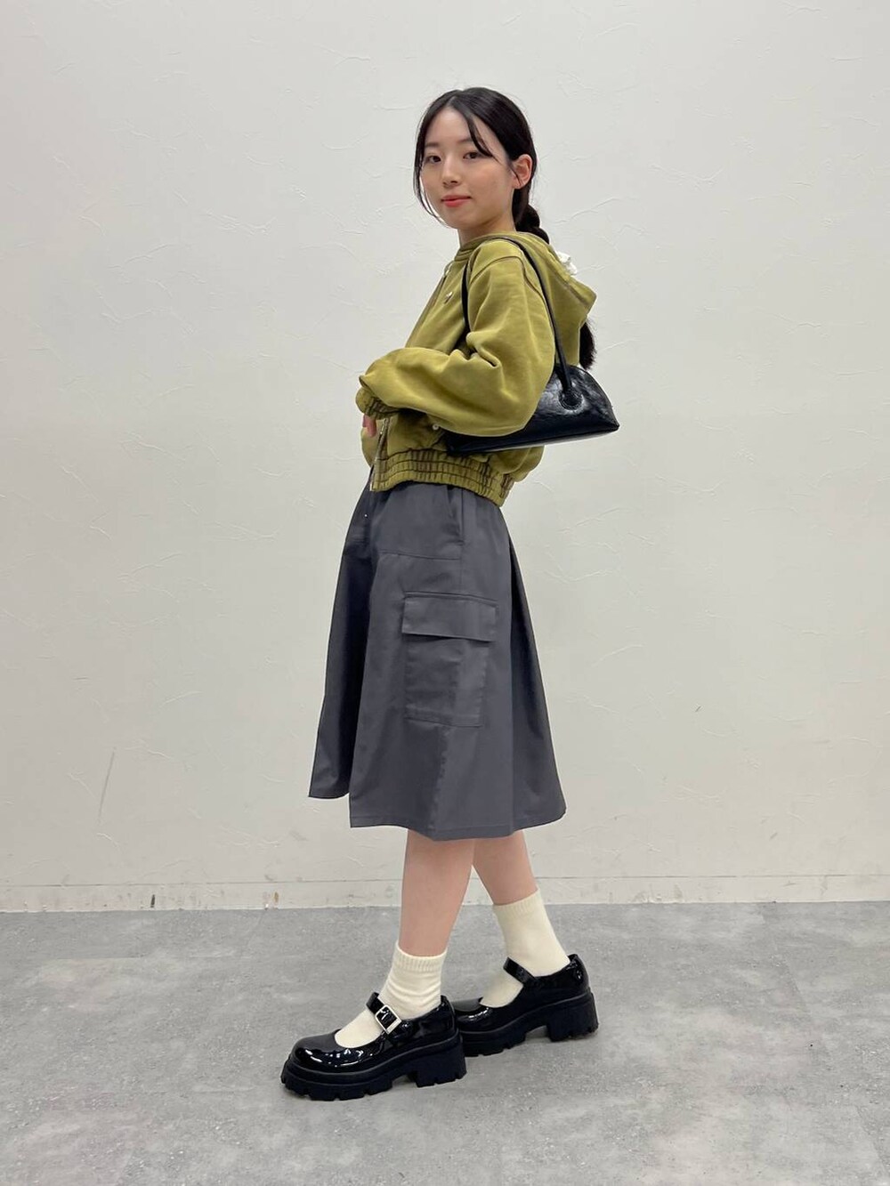 グレー系のスカート、ブラック系のローファー、グリーン系のパーカーを着用したレディースの冬コーディネートの4枚目の写真