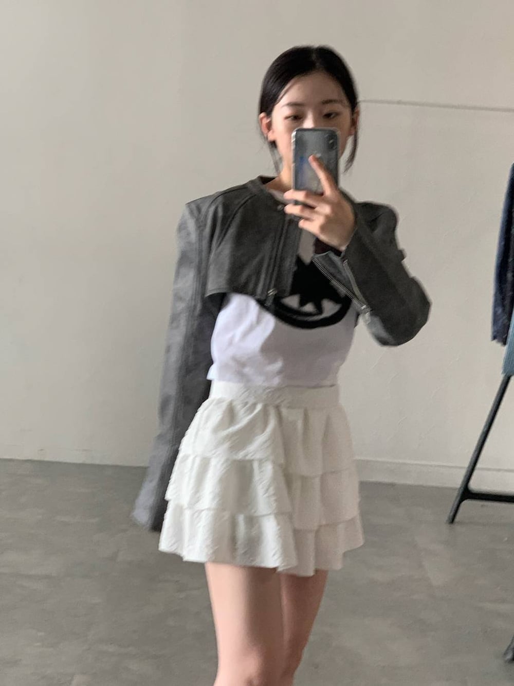 グレー系のライダースジャケット、ホワイト系のスカート、ホワイト系のTシャツ/カットソーを着用したレディースの秋コーディネートの6枚目の写真