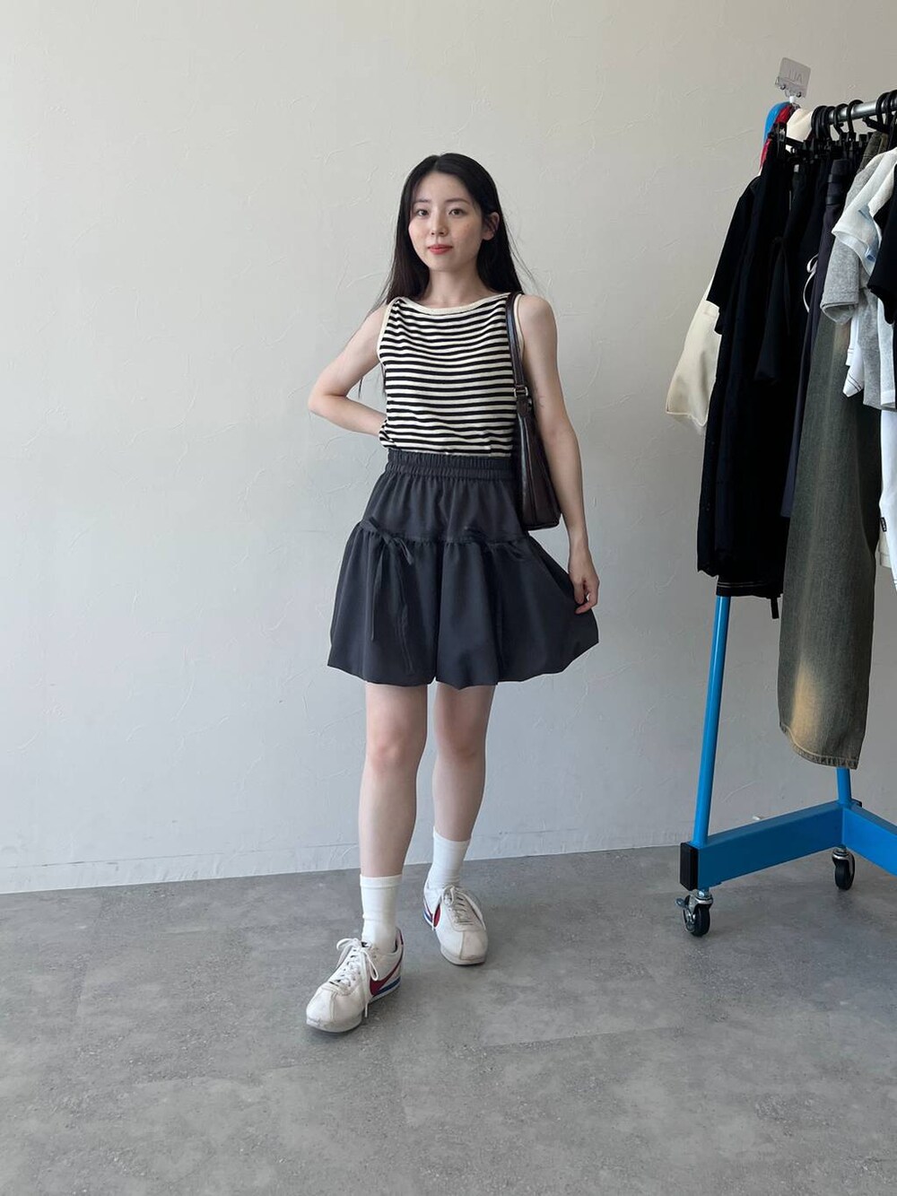 ベージュ系のTシャツ/カットソー、ベージュ系のショルダーバッグ、グレー系のスカートを着用したレディースの春コーディネートの2枚目の写真