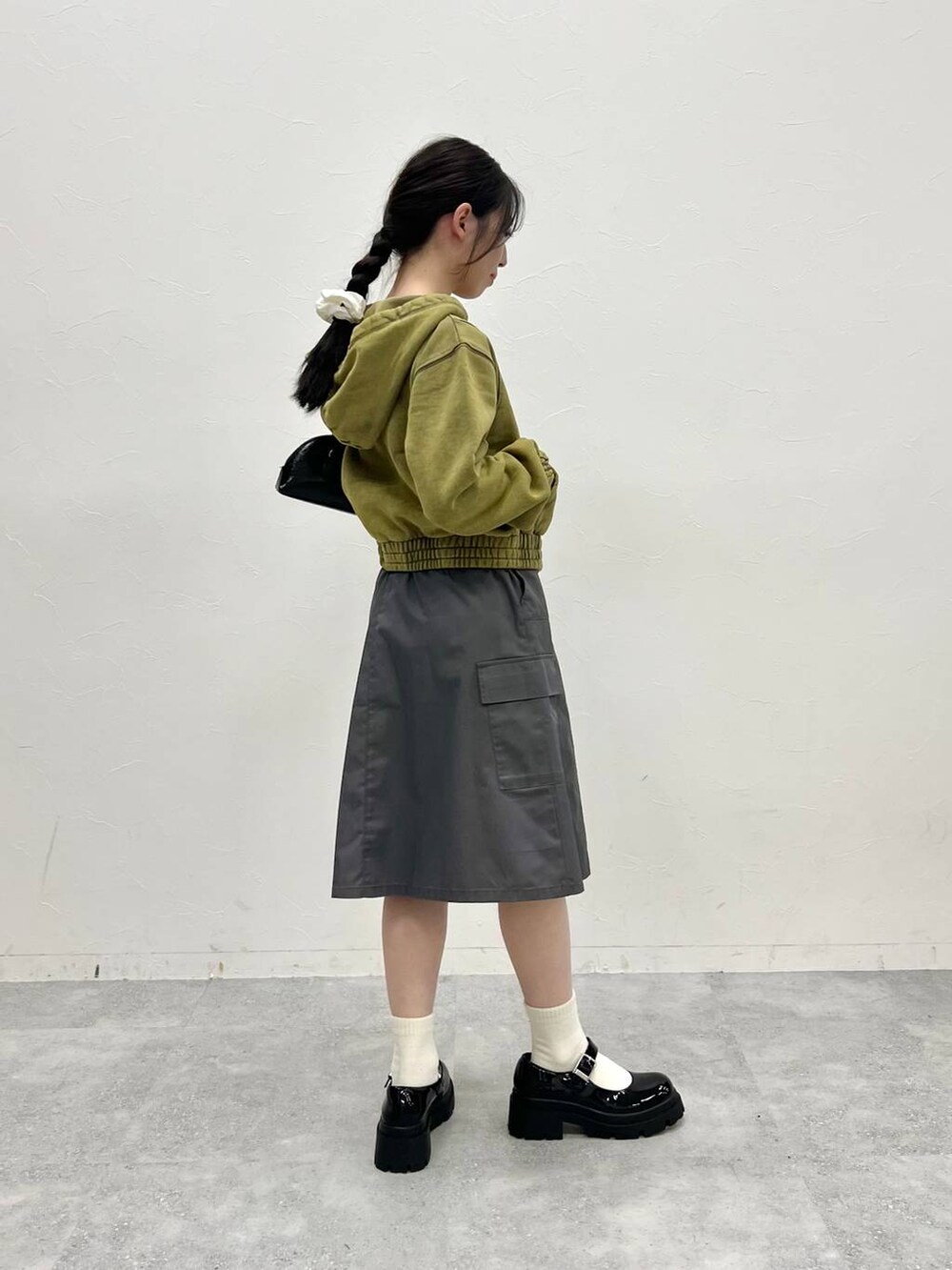 グレー系のスカート、ブラック系のローファー、グリーン系のパーカーを着用したレディースの冬コーディネートの5枚目の写真