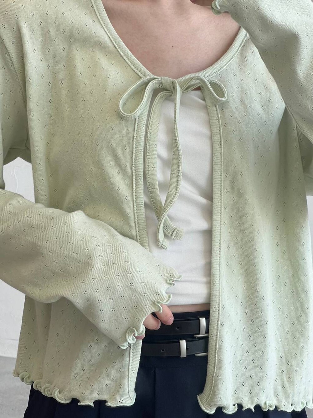 ベージュ系のバックパック/リュック、ブルー系のスカート、グリーン系のカーディガン/ボレロを着用したレディースの春コーディネートの8枚目の写真