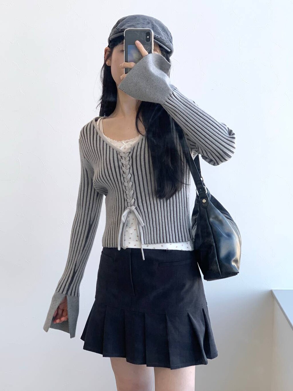 グレー系のカーディガン/ボレロ、グレー系のスカート、ブラック系のハンドバッグを着用したレディースの冬コーディネートの6枚目の写真