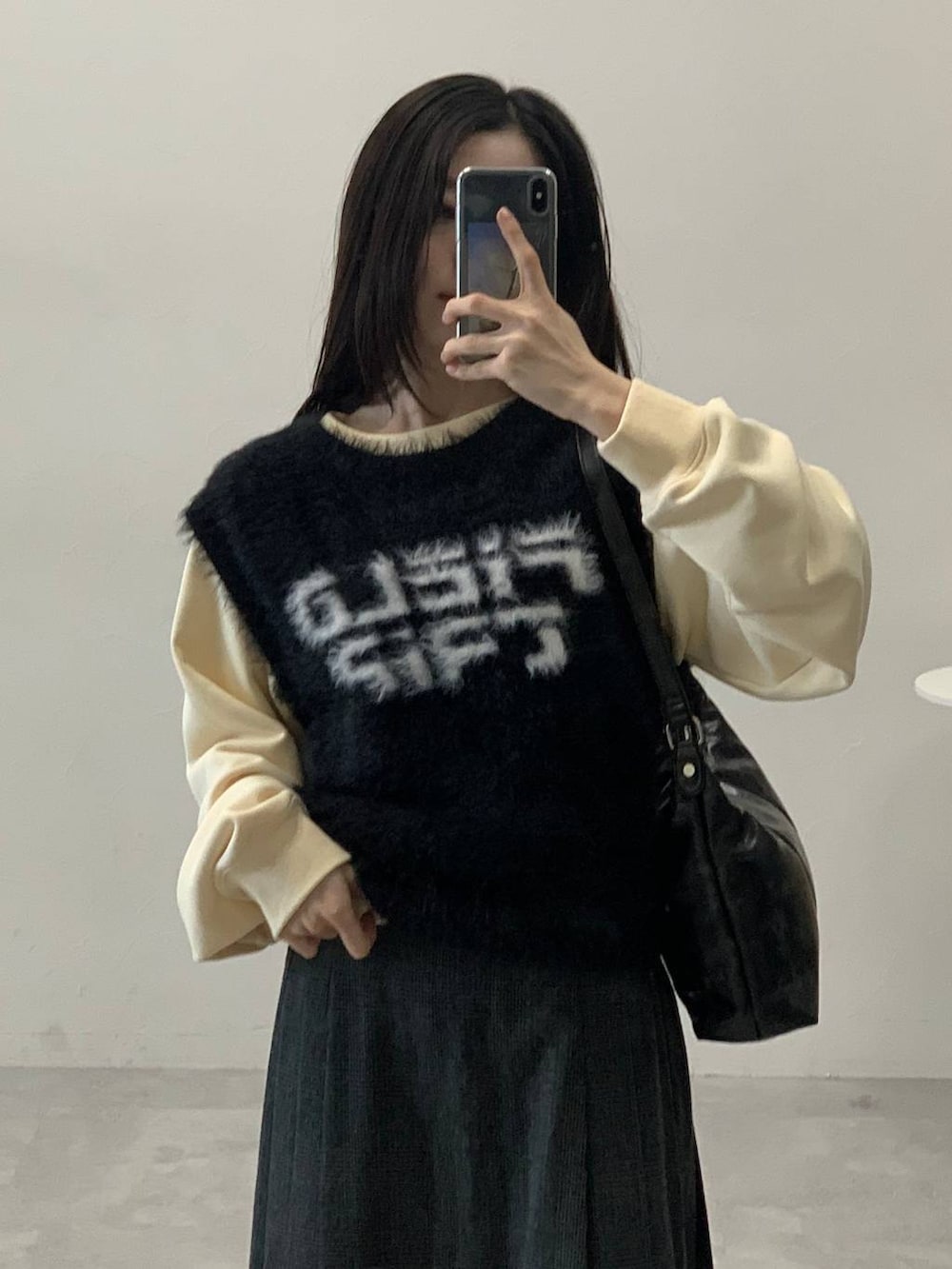 ベージュ系のスウェット、グレー系のスカート、ブラック系のハンドバッグを着用したレディースの冬コーディネートの8枚目の写真