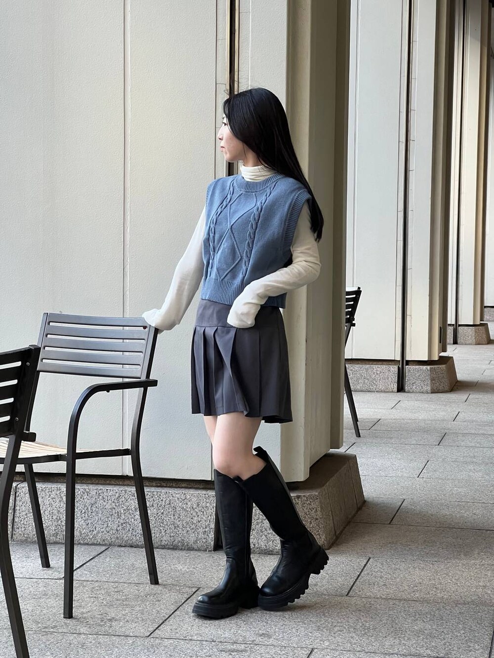 ブルー系のベスト、ブラック系のブーツ、ベージュ系のTシャツ/カットソーを着用したレディースの冬コーディネートの4枚目の写真