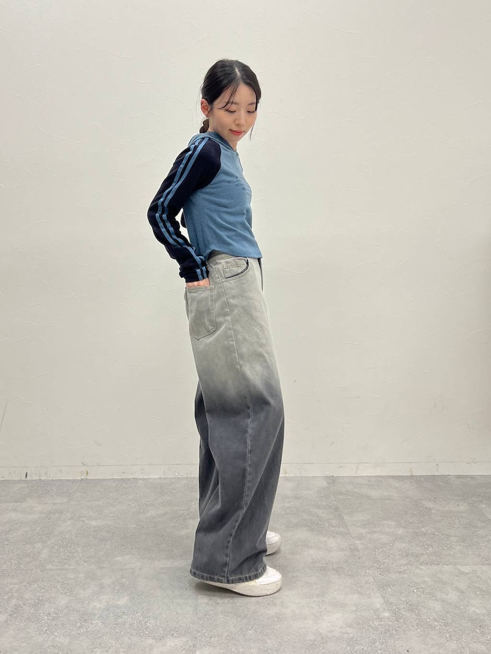 ブラック系のデニムパンツ、ホワイト系のスニーカー、ブルー系のTシャツ/カットソーを着用したレディースの冬コーディネートの4枚目の写真