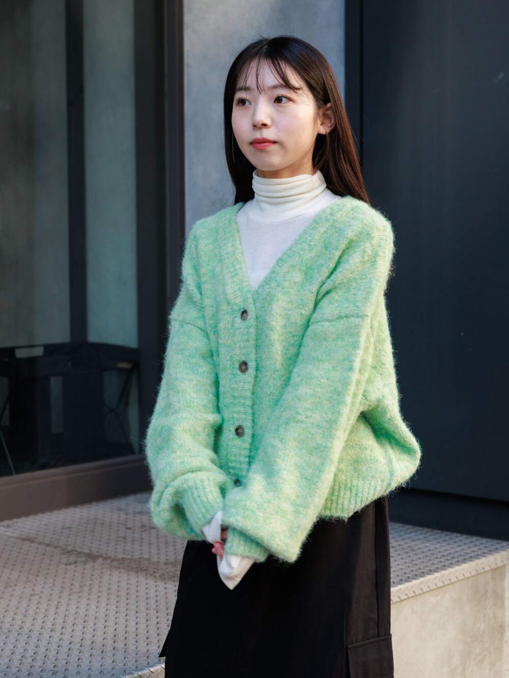 ブラック系のブーツ、ブラック系のスカート、グリーン系のカーディガン/ボレロを着用したレディースの冬コーディネートの4枚目の写真