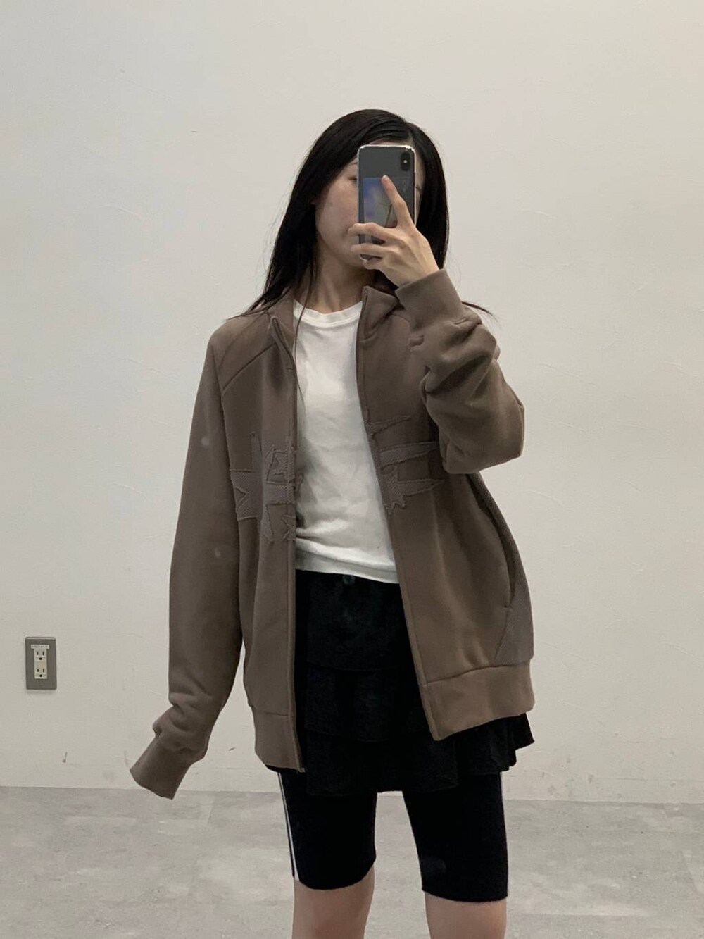 ブラック系のスカート、ベージュ系のパーカー、ブラック系のその他パンツを着用したレディースの秋コーディネートの3枚目の写真