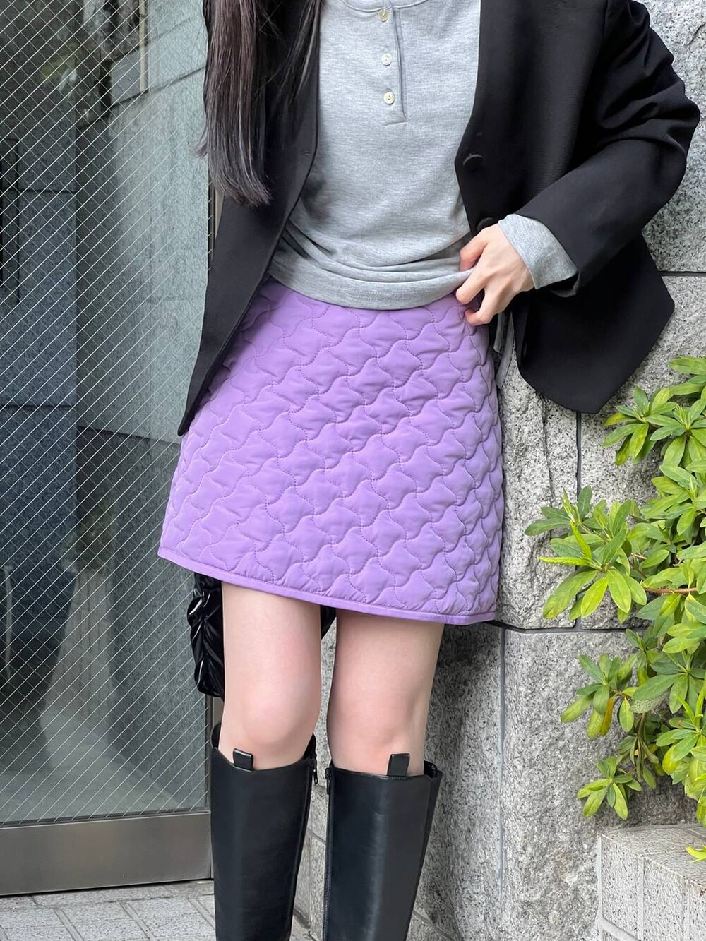 ブラック系のブーツ、パープル系のスカート、ブラック系のノーカラージャケットを着用したレディースの冬コーディネートの4枚目の写真