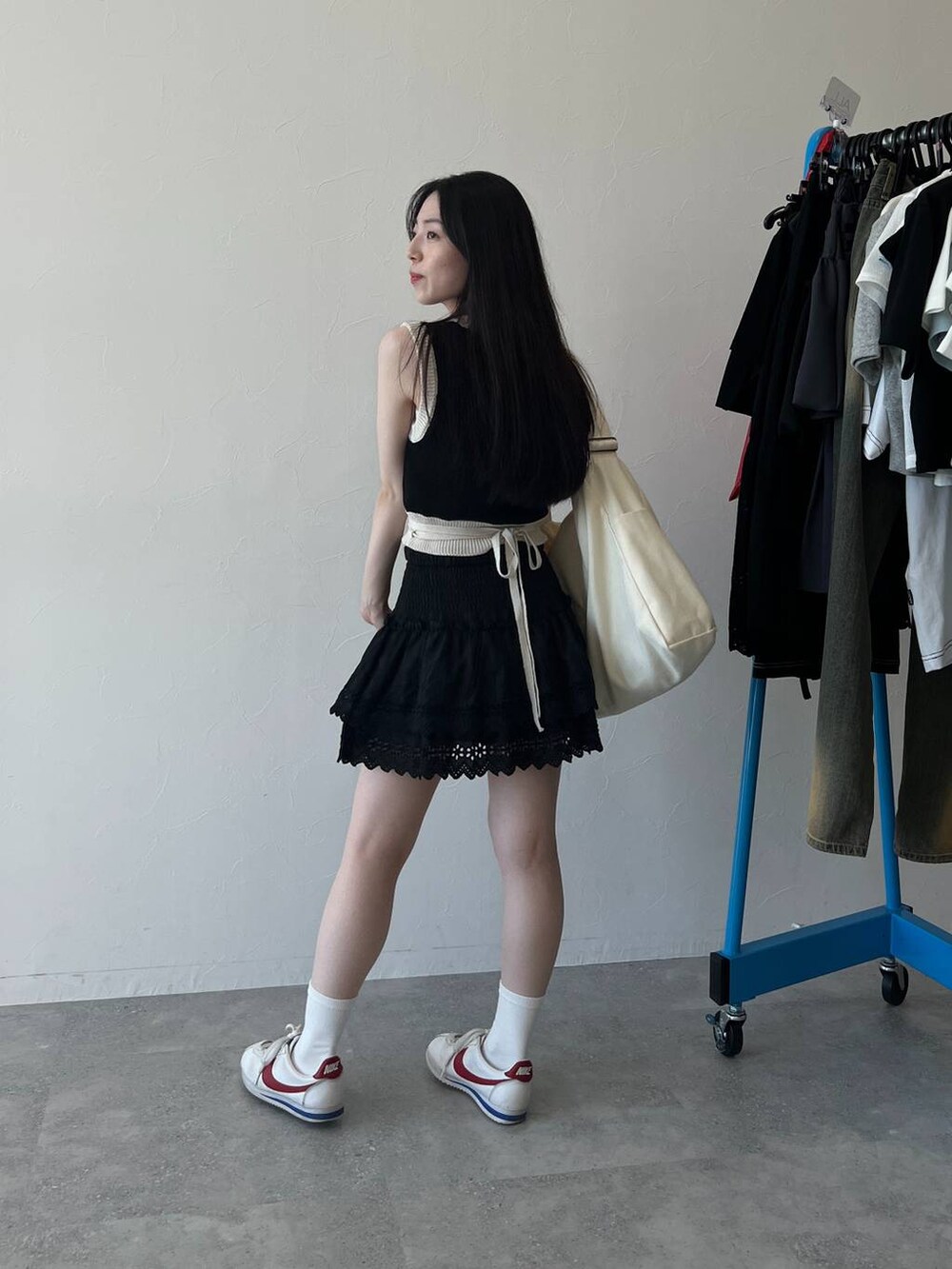 ブラック系のスカート、ブラック系のベスト、ベージュ系のショルダーバッグを着用したレディースの春コーディネートの3枚目の写真