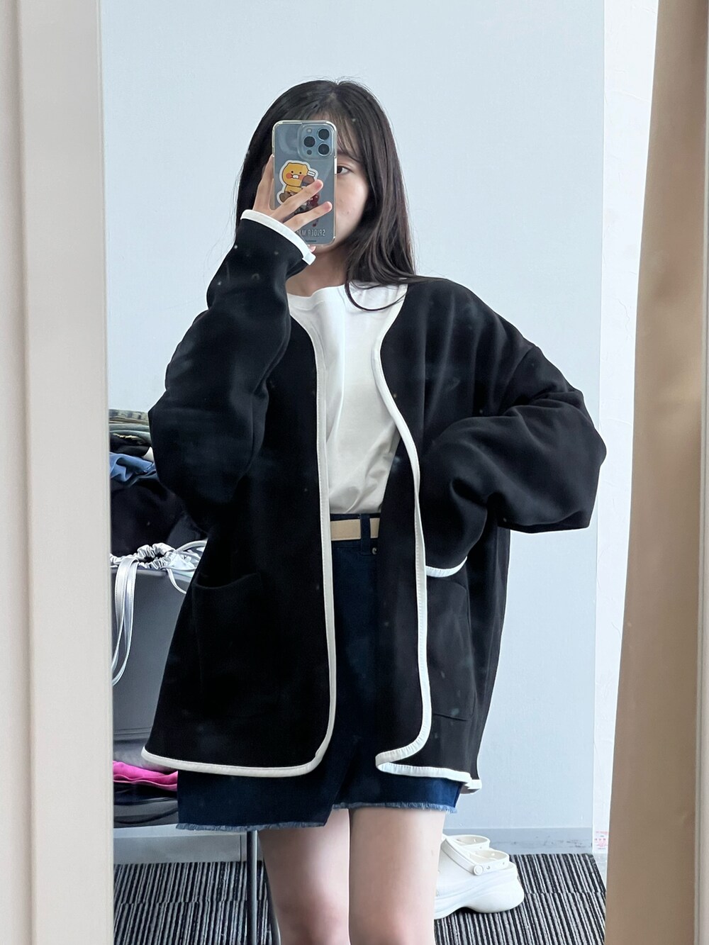 ブラック系のカーディガン/ボレロ、ホワイト系のTシャツ/カットソー、ブルー系のデニムスカートを着用したレディースの冬コーディネートの4枚目の写真