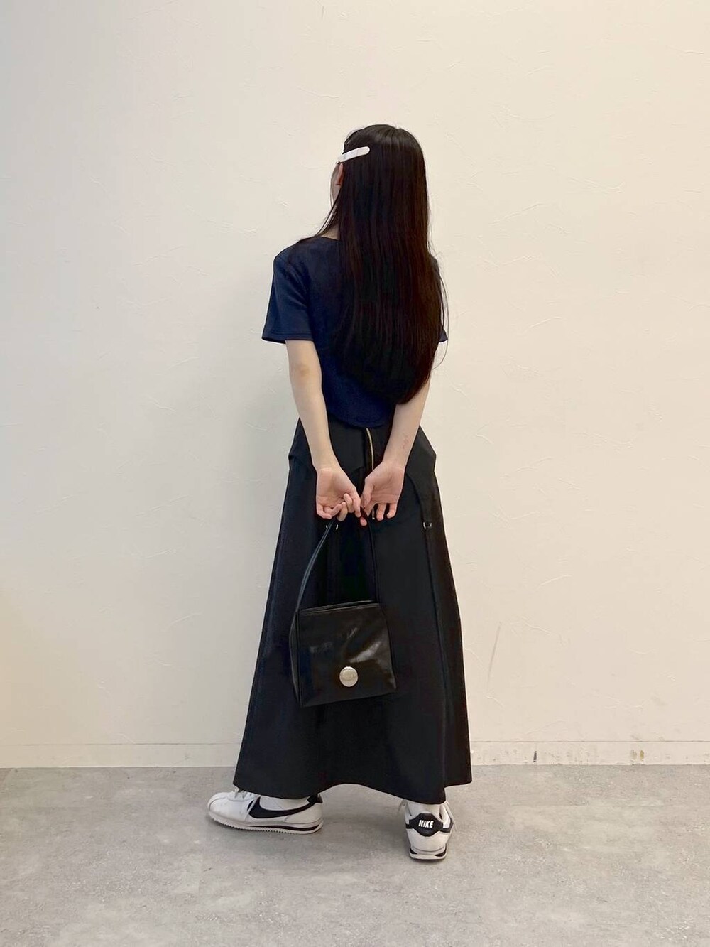 グレー系のスカート、ブラック系のハンドバッグ、ブルー系のTシャツ/カットソーを着用したレディースの夏コーディネートの3枚目の写真