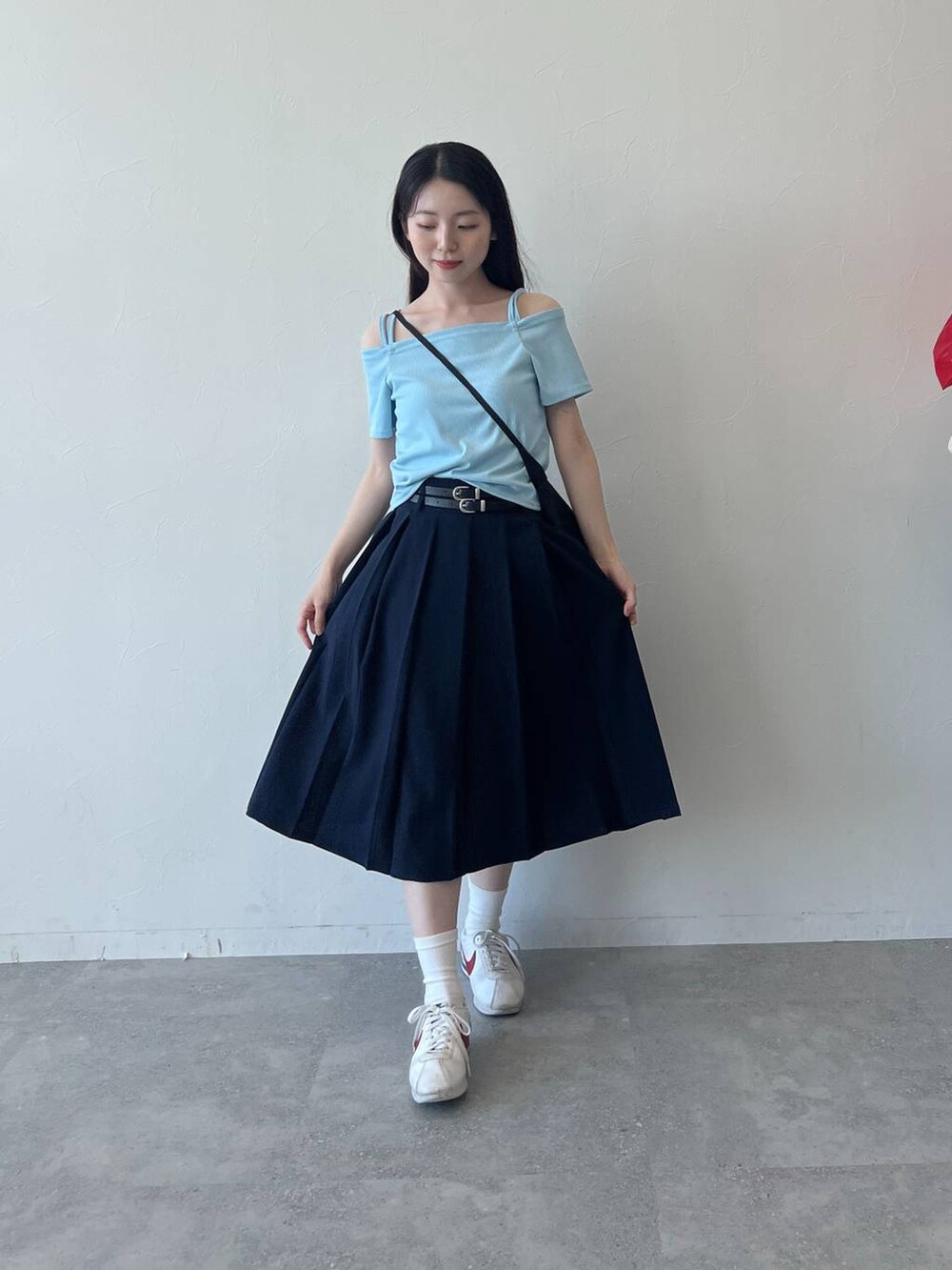 ブルー系のスカート、ブラック系のショルダーバッグ、ブルー系のTシャツ/カットソーを着用したレディースの春コーディネートの2枚目の写真