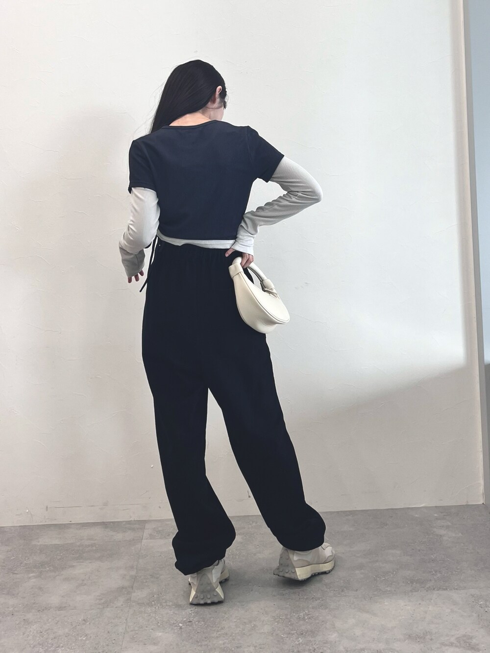 ホワイト系のスニーカー、ブラック系のスウェットパンツ、ホワイト系のショルダーバッグを着用したレディースの冬コーディネートの3枚目の写真
