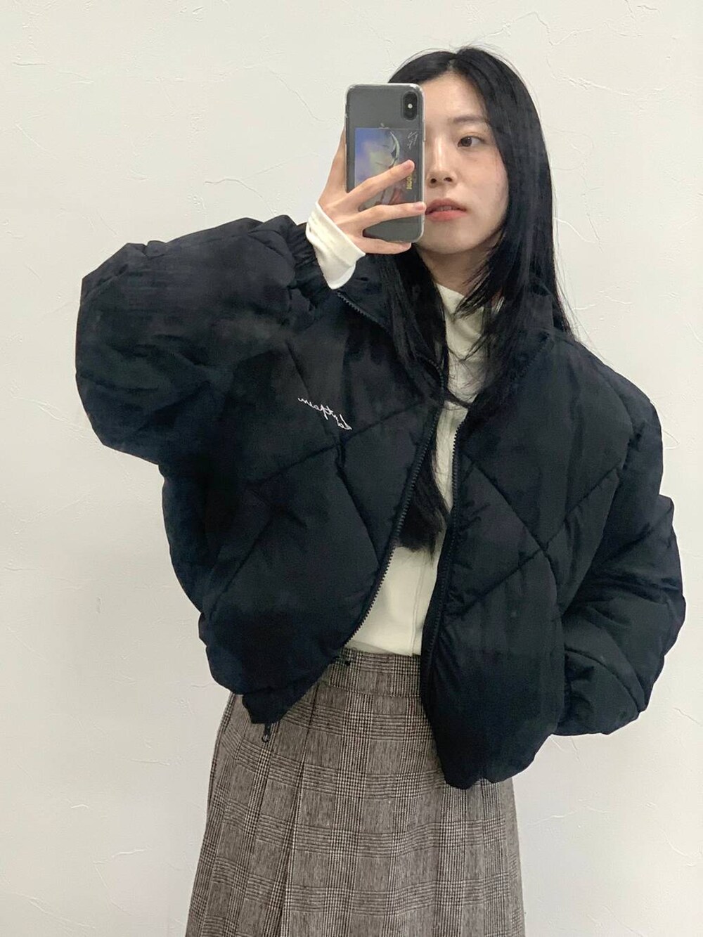 ブラウン系のスカート、ベージュ系のTシャツ/カットソー、ブラック系のダウンジャケット/コートを着用したレディースの冬コーディネートの6枚目の写真