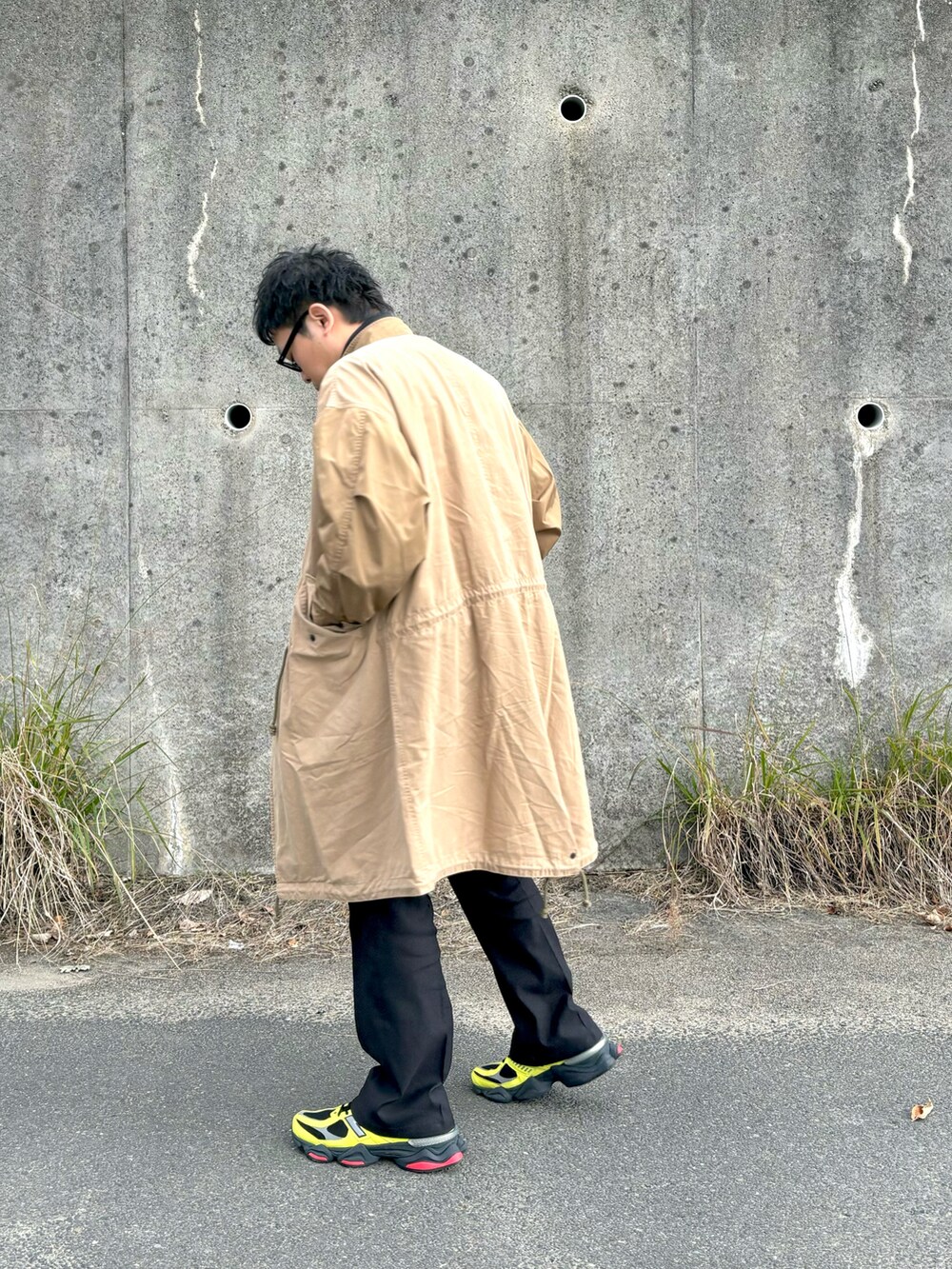 イエロー系のスニーカー、ブラック系のスラックス、ブラウン系のモッズコートを着用したメンズの冬コーディネートの2枚目の写真