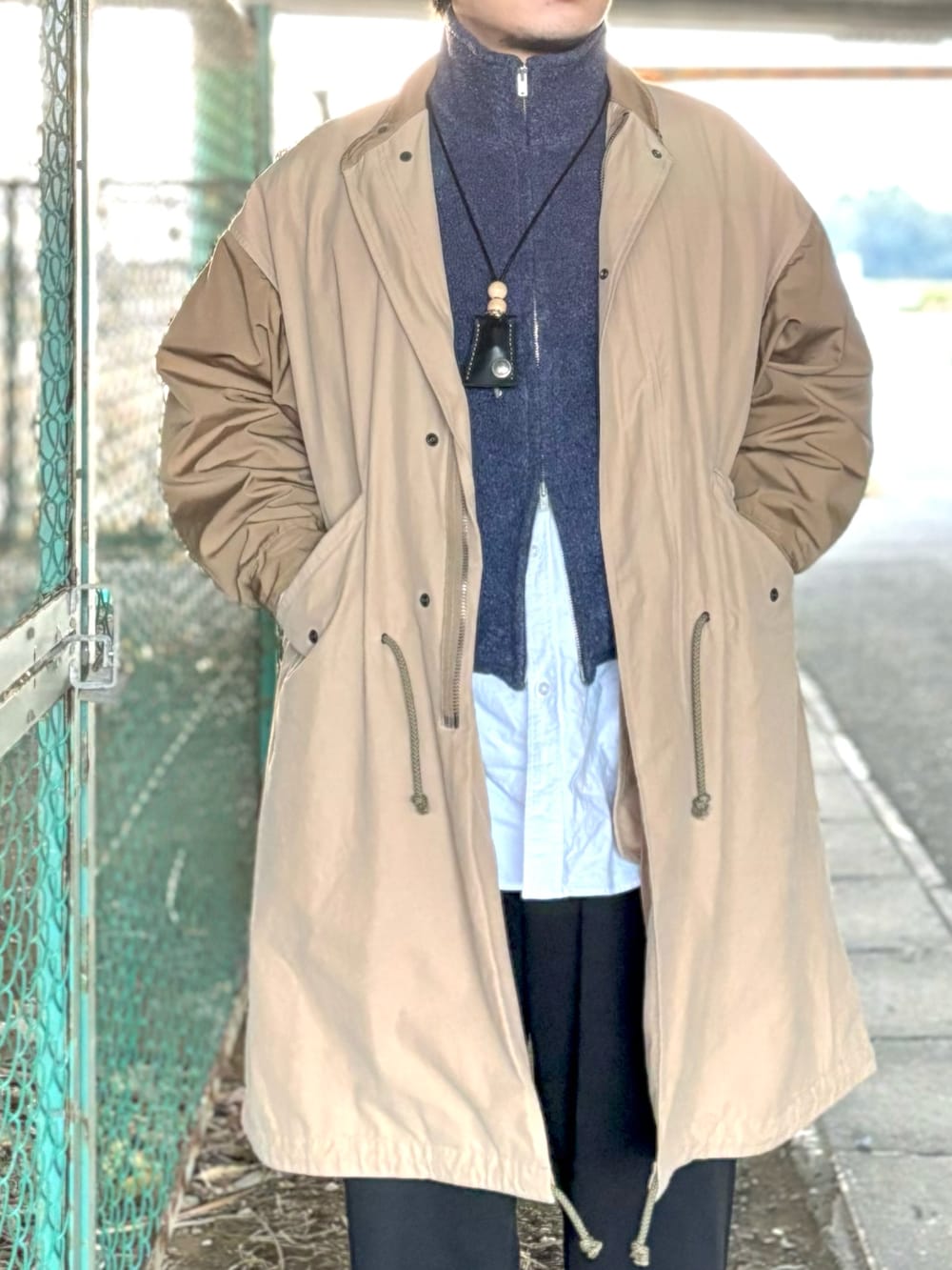 ブラック系のモカシン/デッキシューズ、ブラック系のスウェットパンツ、ブラウン系のモッズコートを着用したメンズの冬コーディネートの2枚目の写真