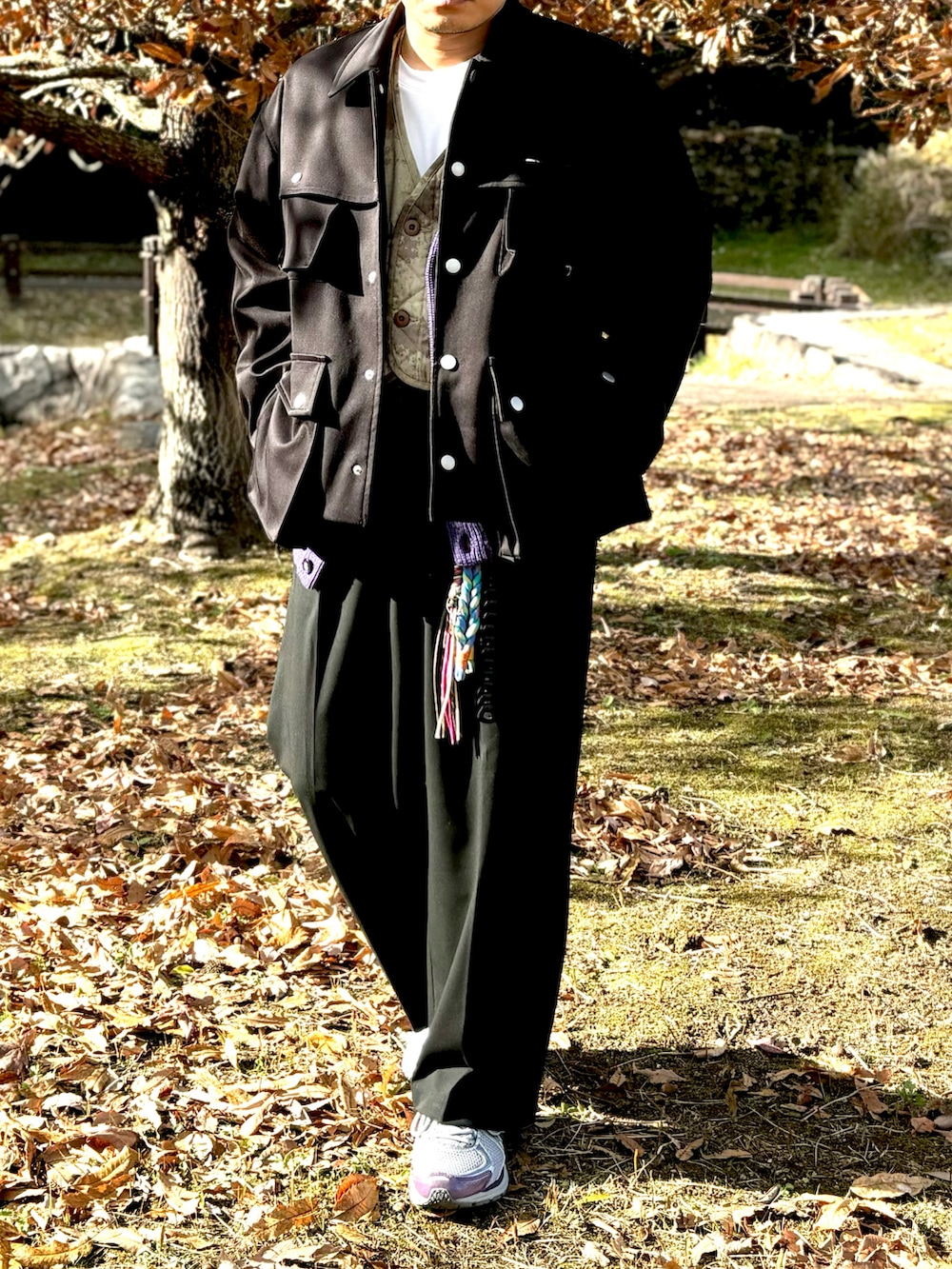 パープル系のスニーカー、ブラック系のスラックス、ブラック系のミリタリージャケットを着用したメンズの冬コーディネートの2枚目の写真