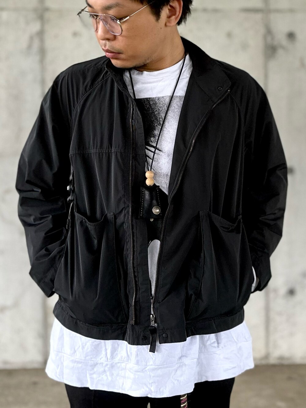 ブラック系のモカシン/デッキシューズ、ブラック系のスラックス、グレー系のブルゾンを着用したメンズの秋コーディネートの2枚目の写真