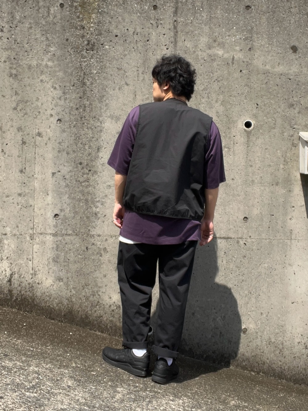 ブラック系のスニーカー、ブラック系のチノパンツ、ブラック系のベストを着用したメンズの夏コーディネートの2枚目の写真