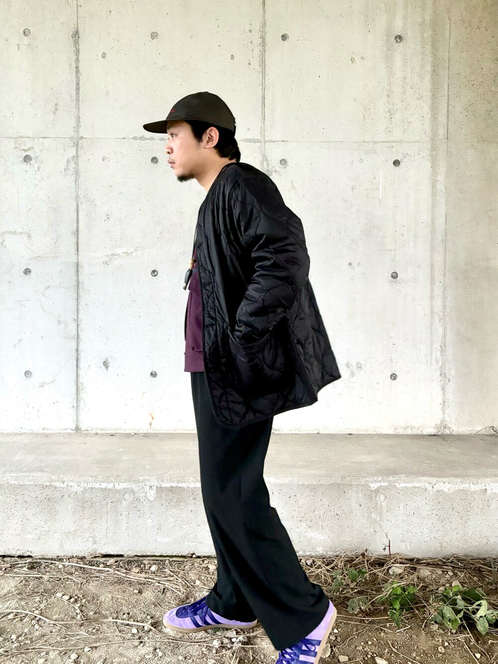 パープル系のスニーカー、ブラック系のスラックス、パープル系のブルゾンを着用したメンズの秋コーディネートの3枚目の写真
