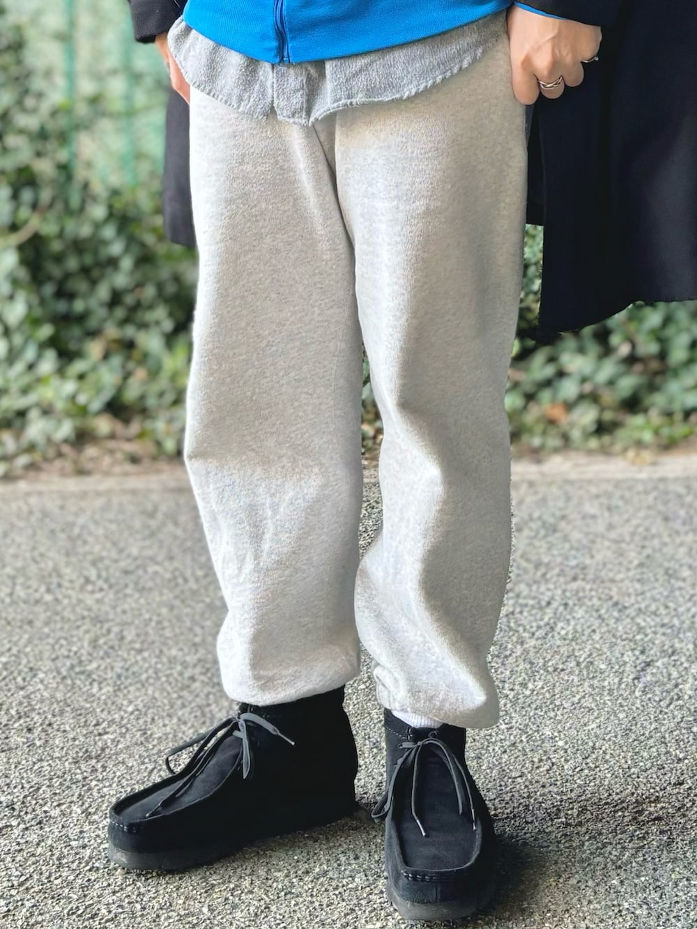 ブラック系のステンカラーコート、ブラック系のモカシン/デッキシューズ、グレー系のスウェットパンツを着用したメンズの冬コーディネートの5枚目の写真