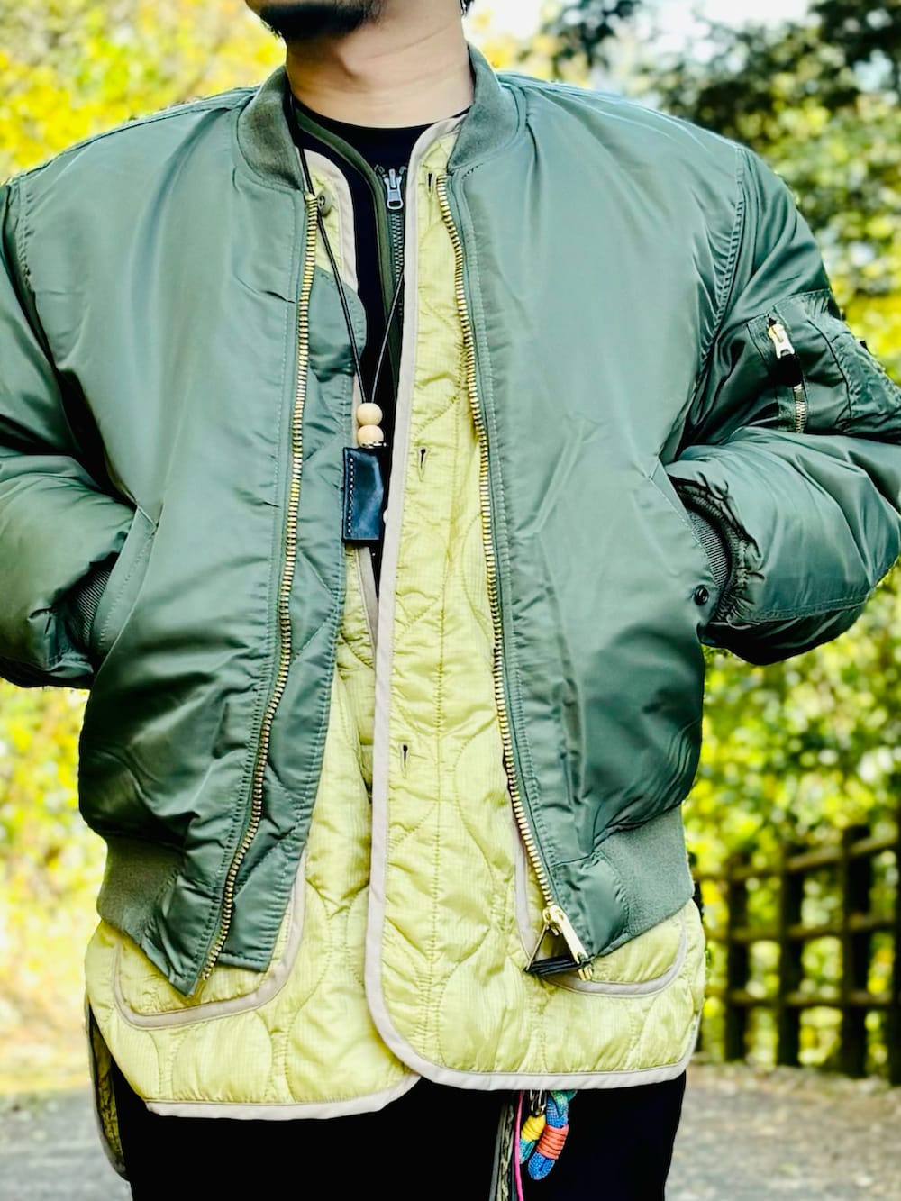 イエロー系のスニーカー、ブラック系のスラックス、グリーン系のMA-1を着用したメンズの冬コーディネートの2枚目の写真