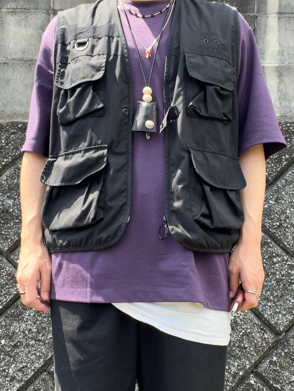 ブラック系のスニーカー、ブラック系のチノパンツ、ブラック系のベストを着用したメンズの夏コーディネートの3枚目の写真