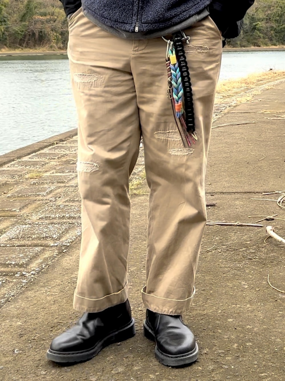 ブラック系のブーツ、ベージュ系のチノパンツ、ブルー系のベストを着用したメンズの冬コーディネートの3枚目の写真