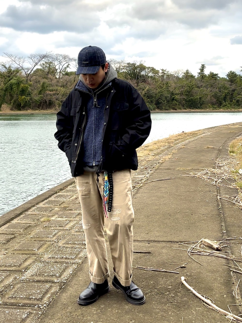 ブラック系のブーツ、ベージュ系のチノパンツ、ブルー系のベストを着用したメンズの冬コーディネートの4枚目の写真