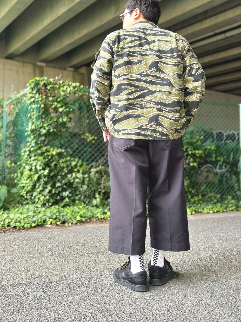 グリーン系のミリタリージャケット、ホワイト系のTシャツ/カットソー、ブラック系のその他パンツを着用したメンズの夏コーディネートの2枚目の写真