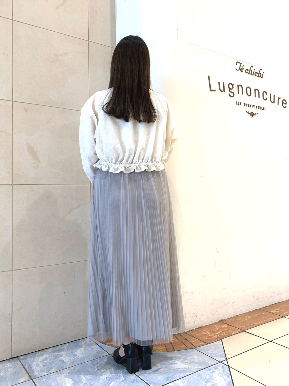 グレー系のスカート、ブラック系のパンプス、ホワイト系のタンクトップを着用したレディースの春コーディネートの3枚目の写真