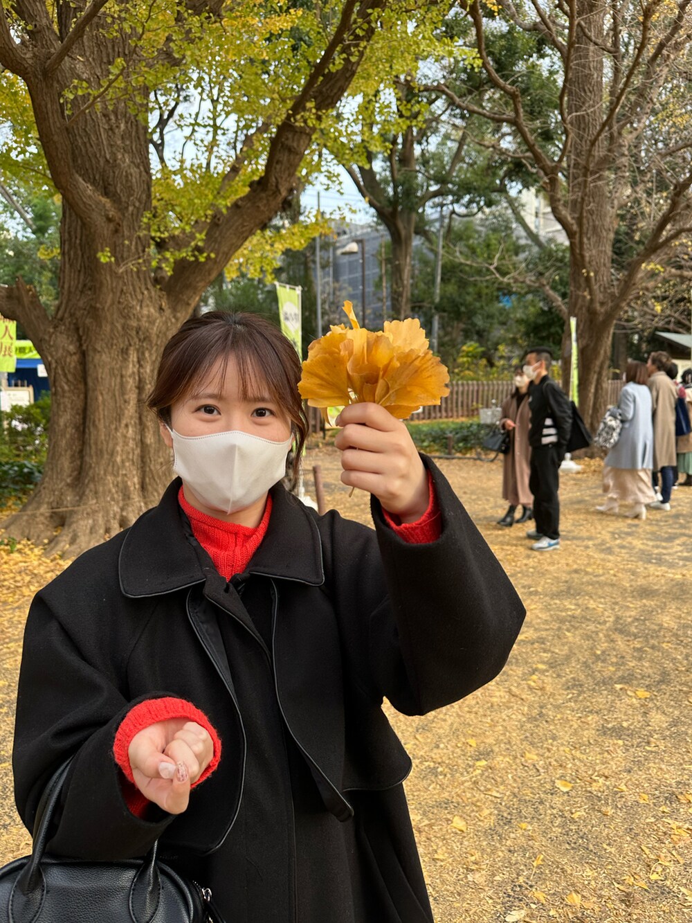 ブラック系のノーカラーコート、ホワイト系のスニーカーを着用したレディースの冬コーディネートの2枚目の写真