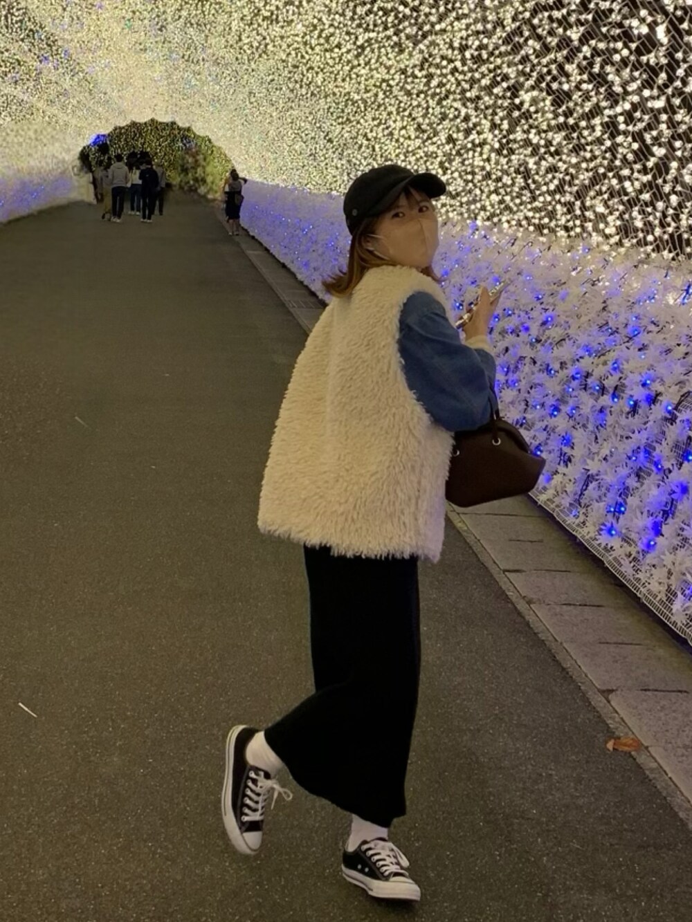 ブラック系のスニーカー、ブラウン系のショルダーバッグ、ホワイト系のベストを着用したレディースの秋コーディネートの2枚目の写真