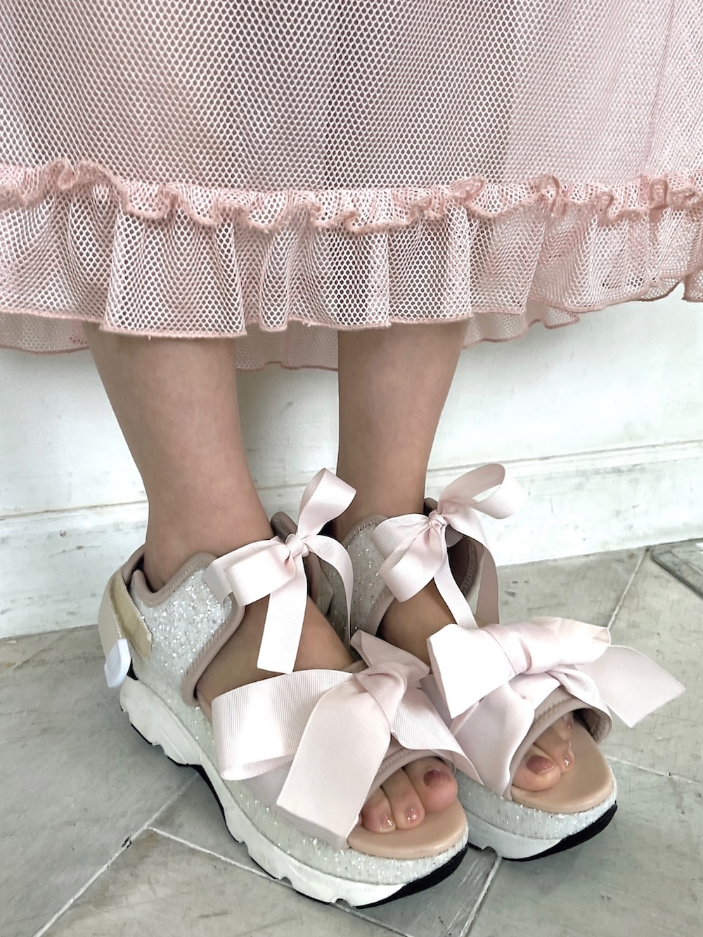 ピンク系のサンダル、ピンク系のTシャツ/カットソー、ホワイト系のスカートを着用したレディースの春コーディネートの7枚目の写真