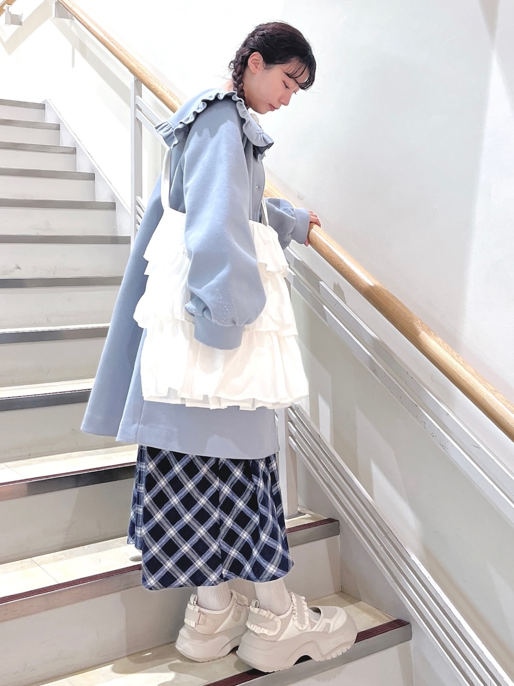 ブルー系のチェスターコート、ブルー系のワンピース、ホワイト系のショルダーバッグを着用したレディースの冬コーディネートの2枚目の写真