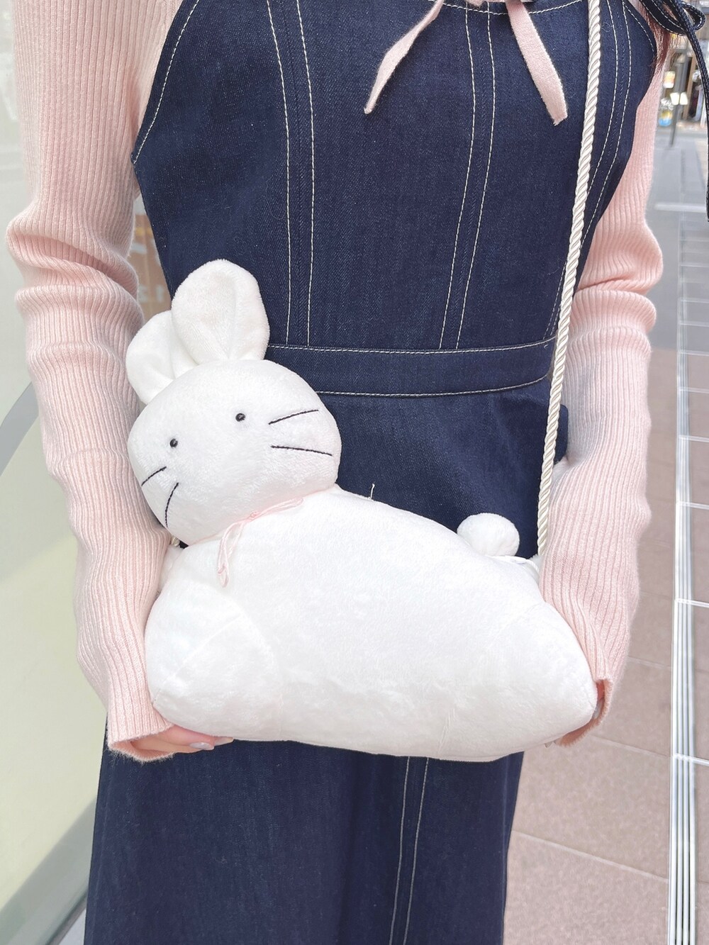 ピンク系のニット/セーター、ブルー系のワンピース、ホワイト系のショルダーバッグを着用したレディースの冬コーディネートの9枚目の写真