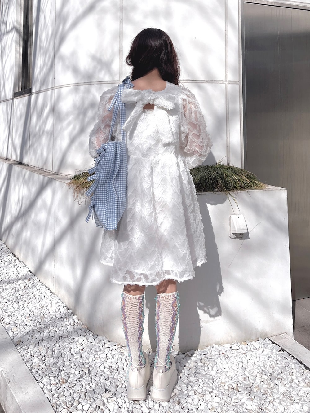 ホワイト系のワンピース、ブルー系のトートバッグ、ホワイト系のバレエシューズを着用したレディースの冬コーディネートの5枚目の写真