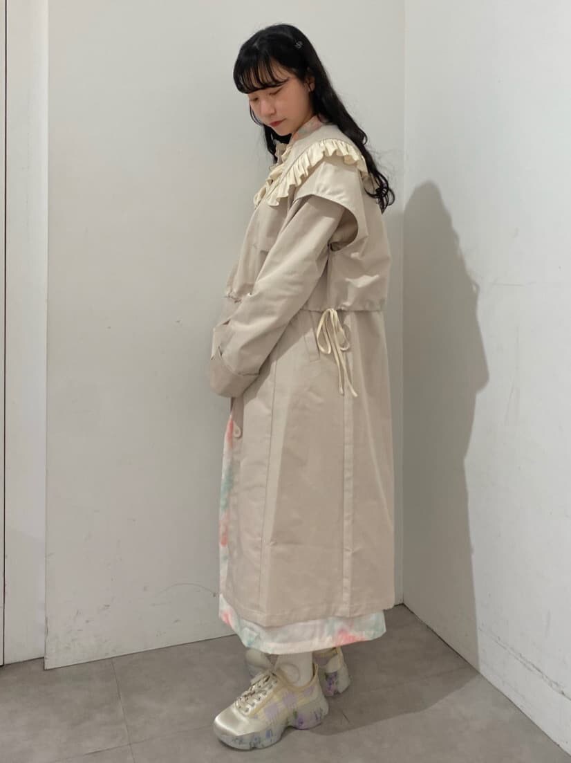 ホワイト系のトレンチコート、ピンク系のワンピース、ホワイト系のスニーカーを着用したレディースの冬コーディネートの2枚目の写真