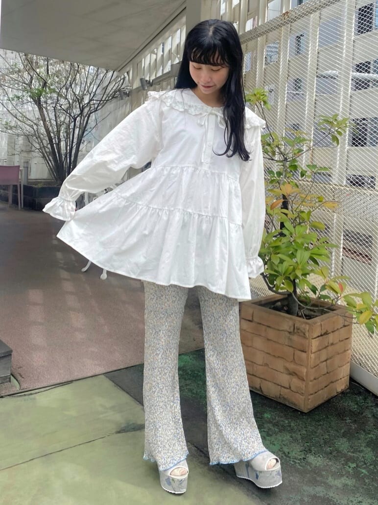 グレー系のサンダル、ホワイト系のチュニック、ブルー系のその他パンツを着用したレディースの秋コーディネートの3枚目の写真