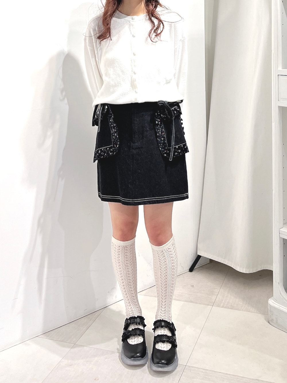 ホワイト系のカーディガン/ボレロ、ブラック系のデニムスカート、ブラック系のスニーカーを着用したレディースの冬コーディネートの5枚目の写真