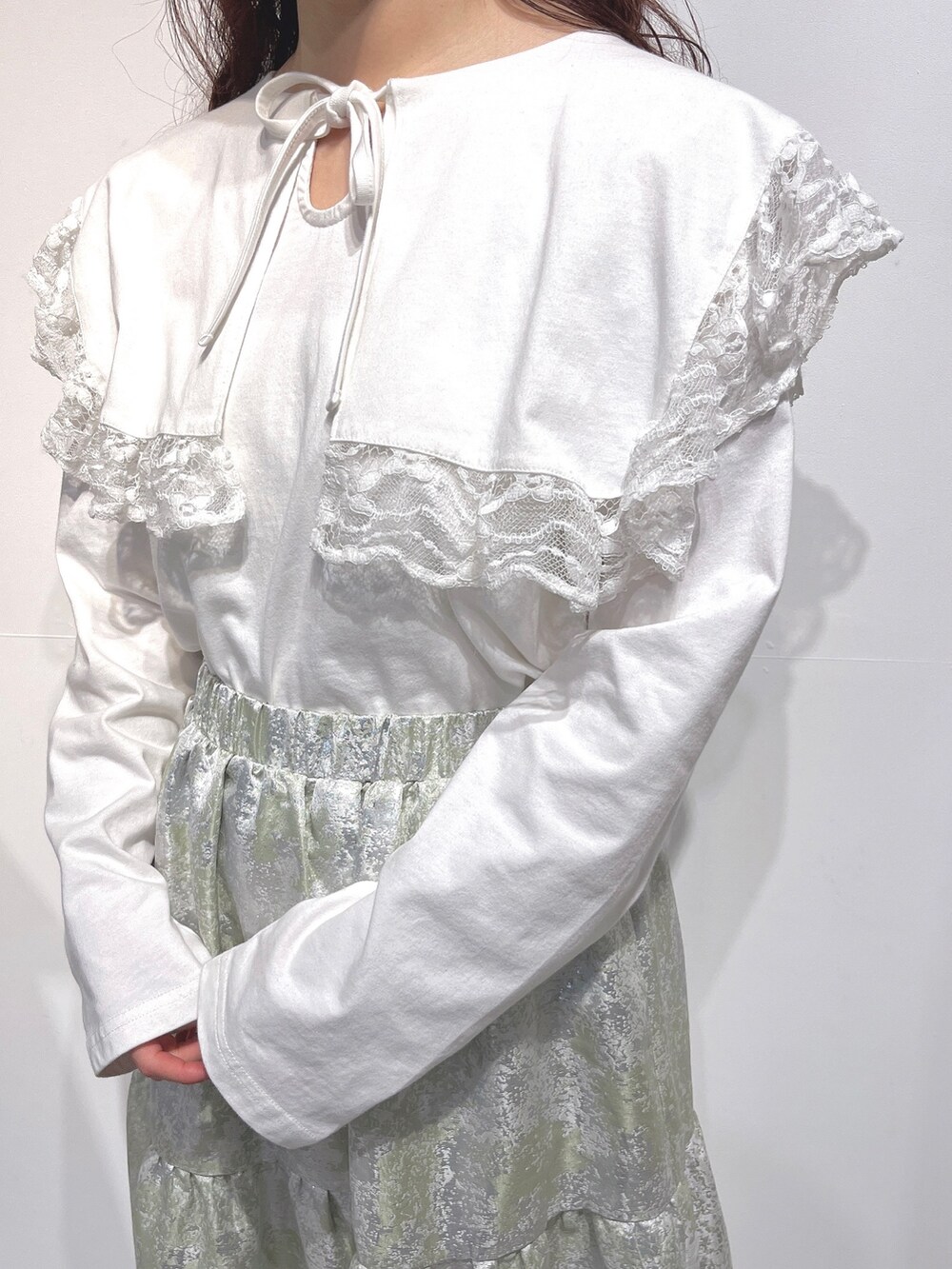 ホワイト系のTシャツ/カットソー、グリーン系のスカート、ホワイト系のパンプスを着用したレディースの冬コーディネートの8枚目の写真