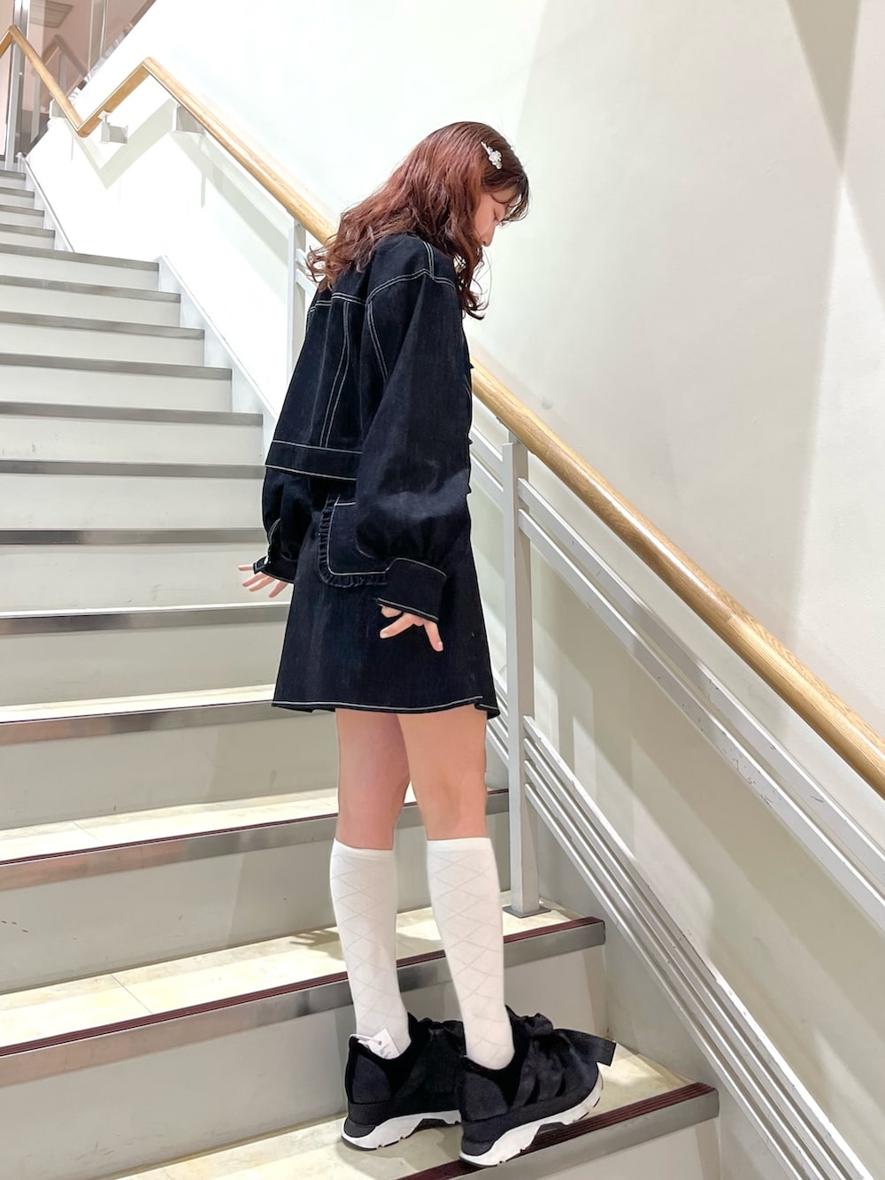 ブラック系のデニムジャケット、ブラック系のデニムスカート、ブラック系のスニーカーを着用したレディースの冬コーディネートの2枚目の写真