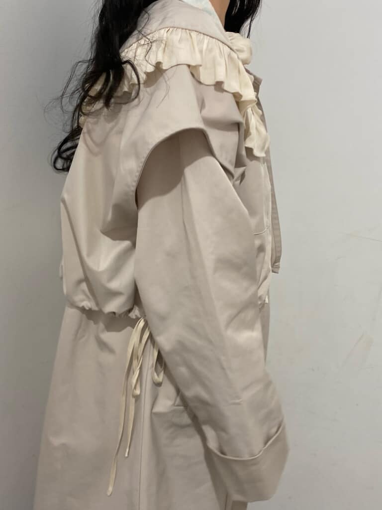 ホワイト系のトレンチコート、ピンク系のワンピース、ホワイト系のスニーカーを着用したレディースの冬コーディネートの6枚目の写真