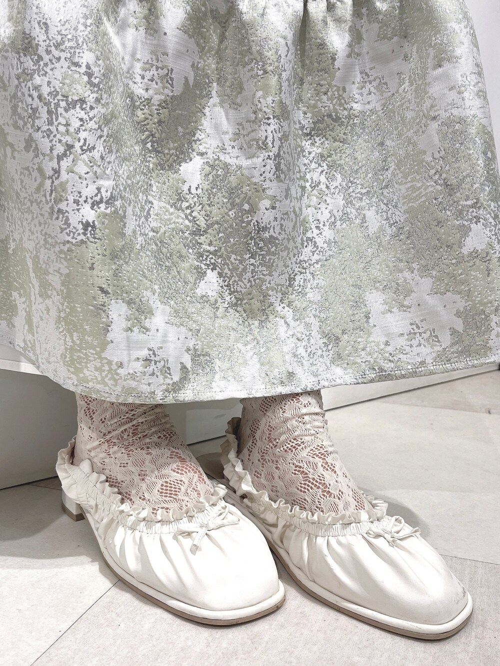 ホワイト系のTシャツ/カットソー、グリーン系のスカート、ホワイト系のパンプスを着用したレディースの冬コーディネートの9枚目の写真