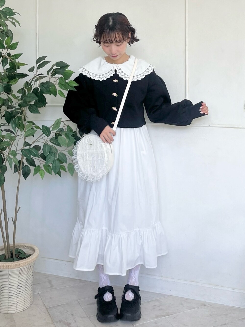 ホワイト系のワンピース、ブラック系のカーディガン/ボレロ、ホワイト系のショルダーバッグを着用したレディースの秋コーディネートの2枚目の写真