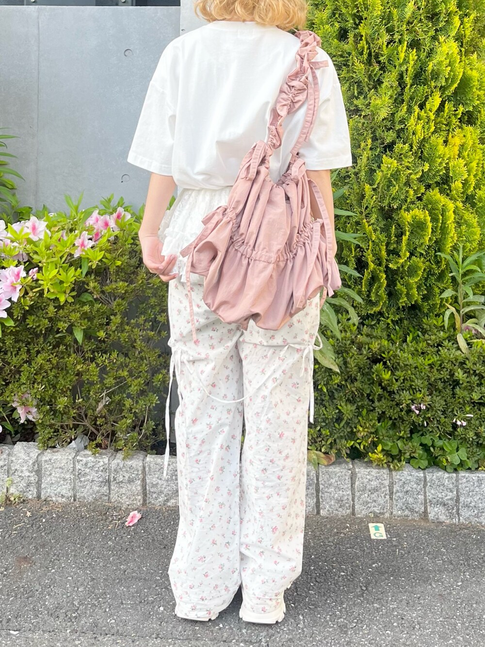 ホワイト系のTシャツ/カットソー、ホワイト系のスラックス、ピンク系のトートバッグを着用したレディースの春コーディネートの5枚目の写真