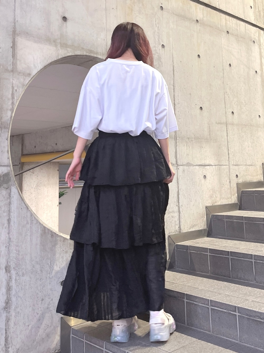 ホワイト系のTシャツ/カットソー、ブラック系のスカート、ベージュ系のスニーカーを着用したレディースの夏コーディネートの3枚目の写真