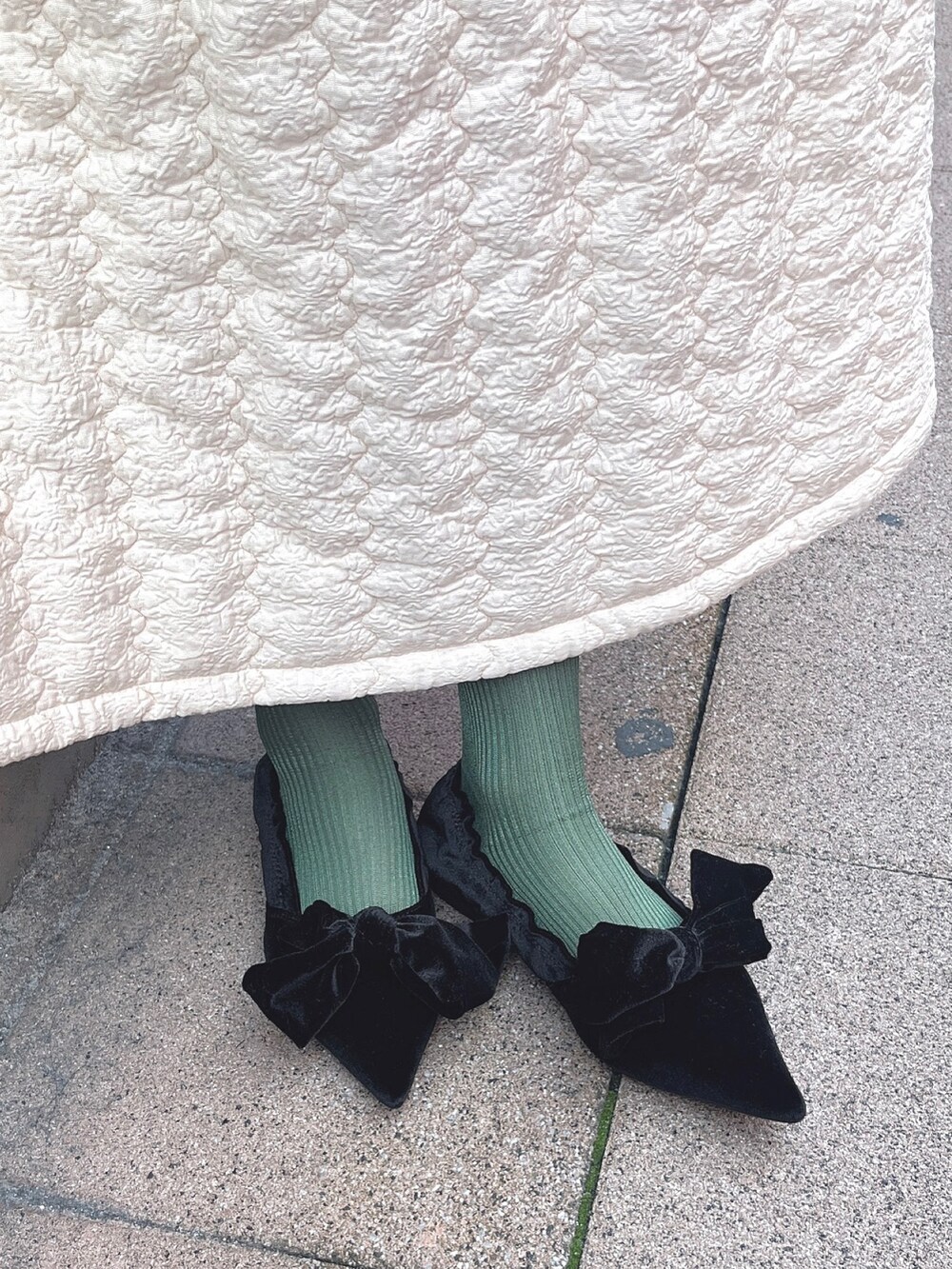 ピンク系のチェスターコート、ブラック系のカーディガン/ボレロ、ホワイト系のワンピースを着用したレディースの冬コーディネートの8枚目の写真