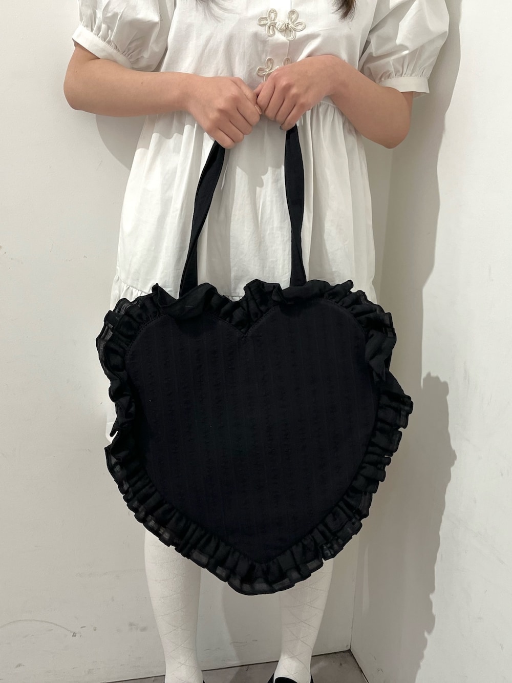 ブラック系のスニーカー、ブラック系のトートバッグ、ホワイト系のワンピースを着用したレディースの春コーディネートの3枚目の写真